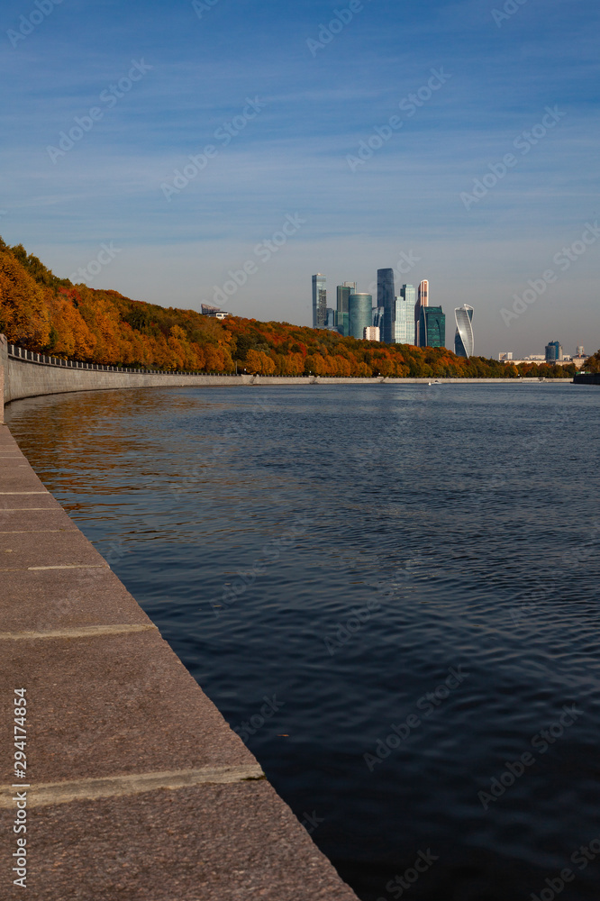 Embankment of the Moscow River, decorated with autumn trees. Moscow City buildings are in the background.