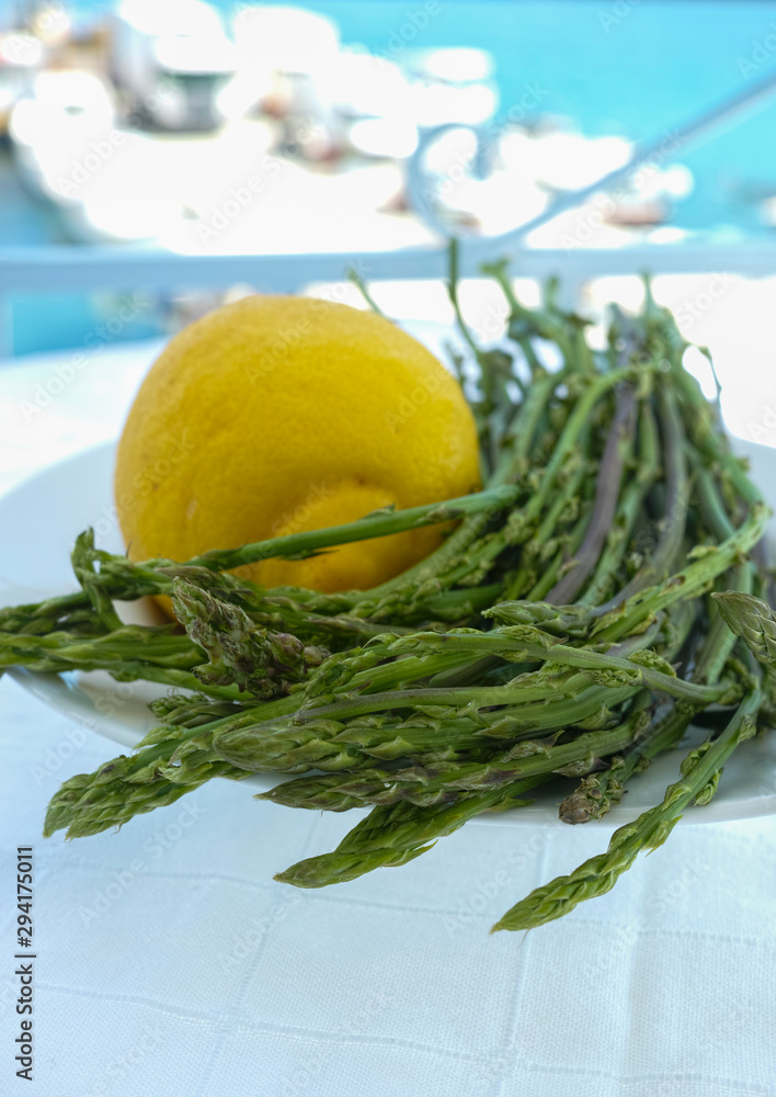 Natural food from forest and mountains in Greece green wild asparagus and lemon on balcony with sea view