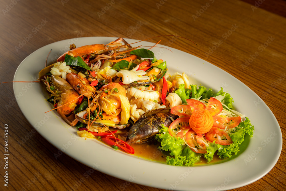 Stir​ fried​ spicy seafood in​ the​ white​ plate.