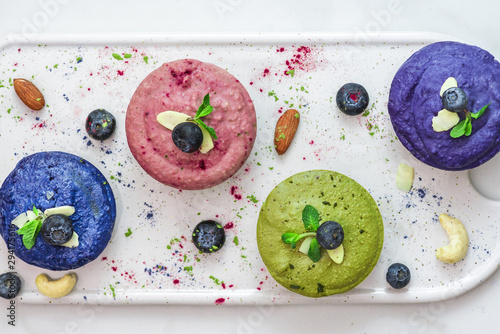 homemade raw vegan colorful cakes with matcha, acai, blue spirulina and butterfky pea tea, fresh berries, mint, nuts photo