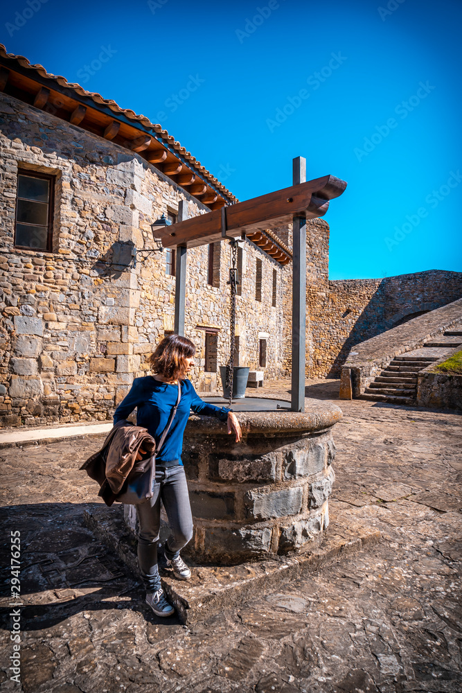 Jaca, Huesca / Spain »; September 29, 2019: A young woman dressed in blue in A well to draw water in the citadel of Jaca