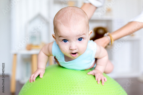Exercise with a child on the ball. Professional baby massage at home.