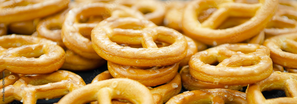 Pretzel with many small cookies scattered on a dark background. Traditional food for Oktoberfest - salt appetizer pretzels on a black background. German pretzel von, Oktoberfest. Pretzel with many small cookies scattered on a dark background. Traditional food for Oktoberfest - salt appetizer pretzels on a black background. German pretzel von, Oktoberfest.