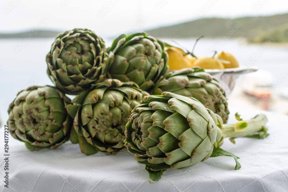 Obraz premium Bunch of fresh raw artichokes heads from artichoke plantation in Argolida, Greece ready to cook with lemon