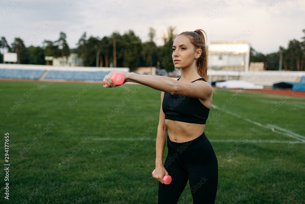 Female runner in sportswear holds dumbbells Female runner in sportswear holds dumbbells