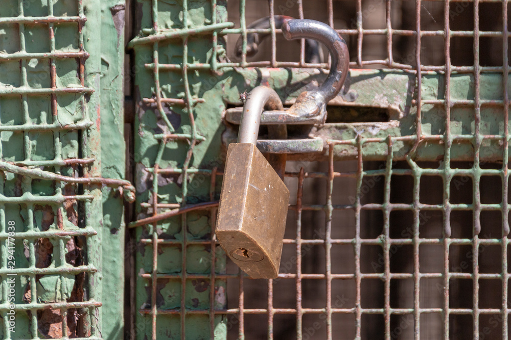 A close up view of a padlock keeping a metal gate closed A close up view of a padlock keeping a metal gate closed