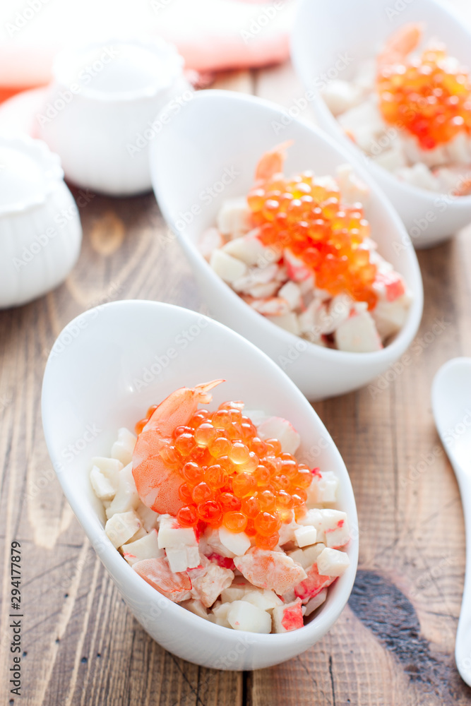 Salad with seafood and red caviar in portioned bowls on a wooden table, selective focus Salad with seafood and red caviar in portioned bowls on a wooden table, selective focus