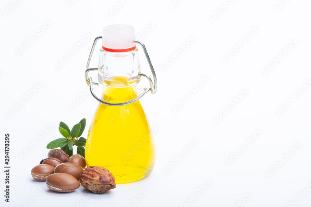Skin and hair care product, natural argan oil in bottle and argan nuts isolated on white background Skin and hair care product, natural argan oil in bottle and argan nuts isolated on white background