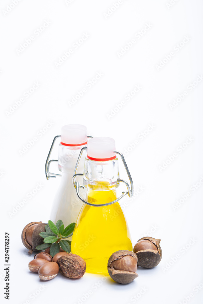 Skin and hair care product, creme or shampoo made from natural argan or macadamia oil in bottle and argan and macadamia  nuts isolated on white background
