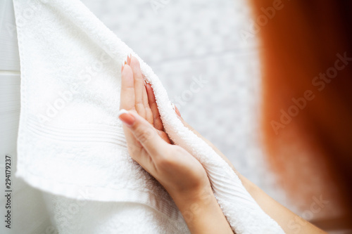Hygiene and hand care. Woman using towel for wiping hands dry after washing in light bathroom at home