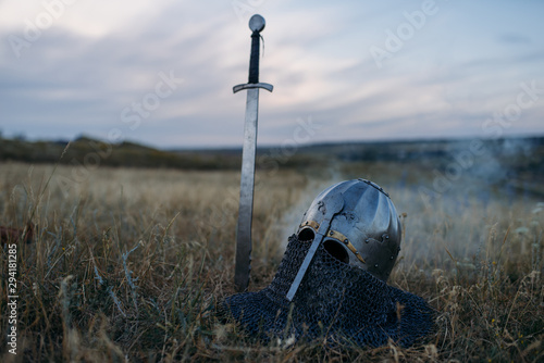 Foto Sword stuck in the ground and metal knight helmet