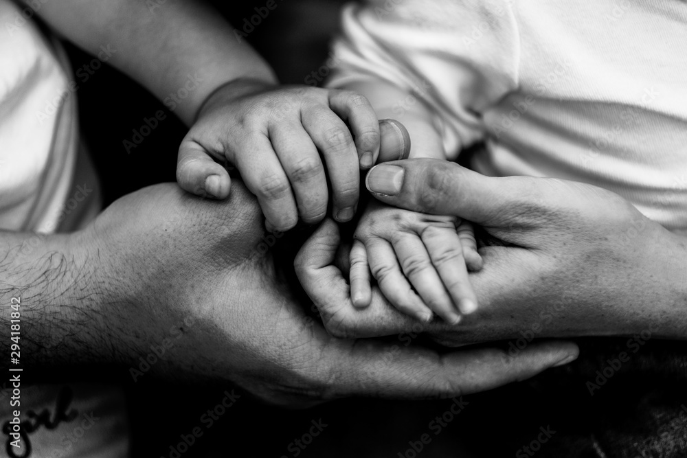Hands of father, mother, daughter keep little feet baby. Friendly happy family, hands families together