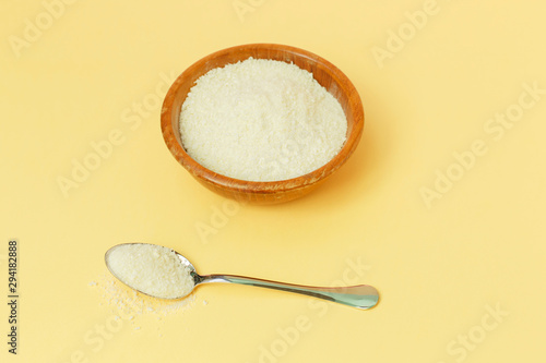 Collagen protein in the bowl and spoon - Hydrolyzed on yellow background
