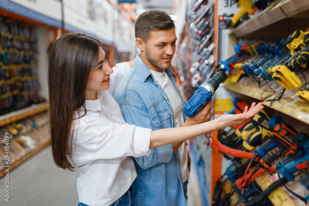 Young couple choosing instrument in hardware store