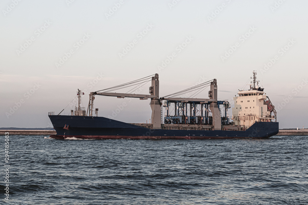 Large industrial cargo ship sailing on the sea against the gray sky