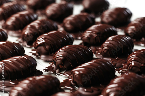 Dates in chocolate, dessert. Confectioner pours chocolate over dessert. Macro, close-up.