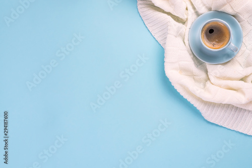 Blue cup of coffee on plaid over the blue paper background with copy space, flat lay. Cozy winter
