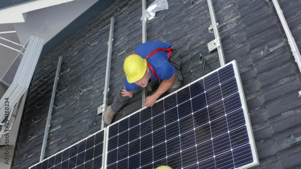 Steady flyover shot of two workers mounting solar panel on its place on the roof Steady flyover shot of two workers mounting solar panel on its place on the roof