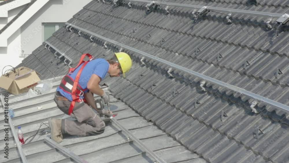 A worker drilling screws for installation of PV solar panels sheets on the rooftop of a house.A static footage.Concept of professionalism,job,energy.(1) A worker drilling screws for installation of PV solar panels sheets on the rooftop of a house.A static footage.Concept of professionalism,job,energy.(1)