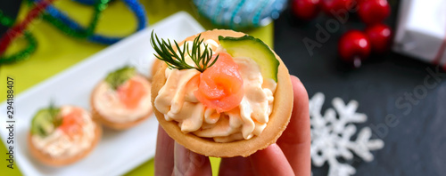 Tartlets with cream cheese and red salted salmon on a white plate for the festive table. Tasty portion light snack for a party. Finger Food.