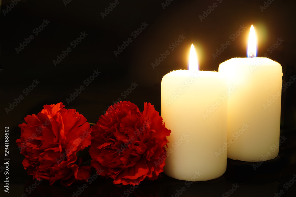 Two burning candles with flowers.