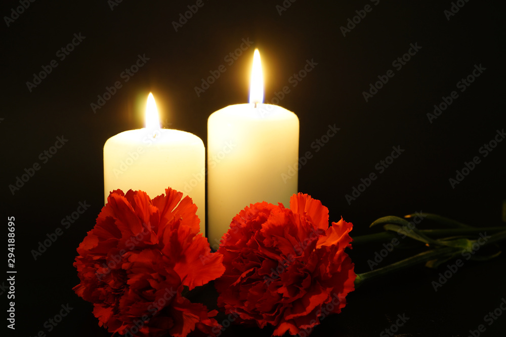 Two burning candles with flowers.