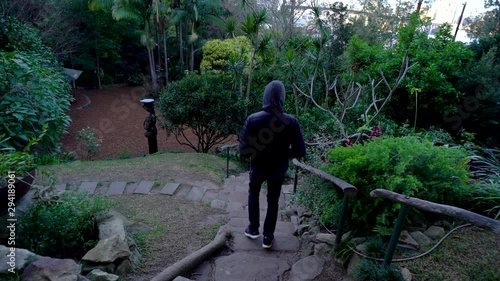 Man in a hoody walking down a set of flagstone stairs in Wendy`s secret garden photo