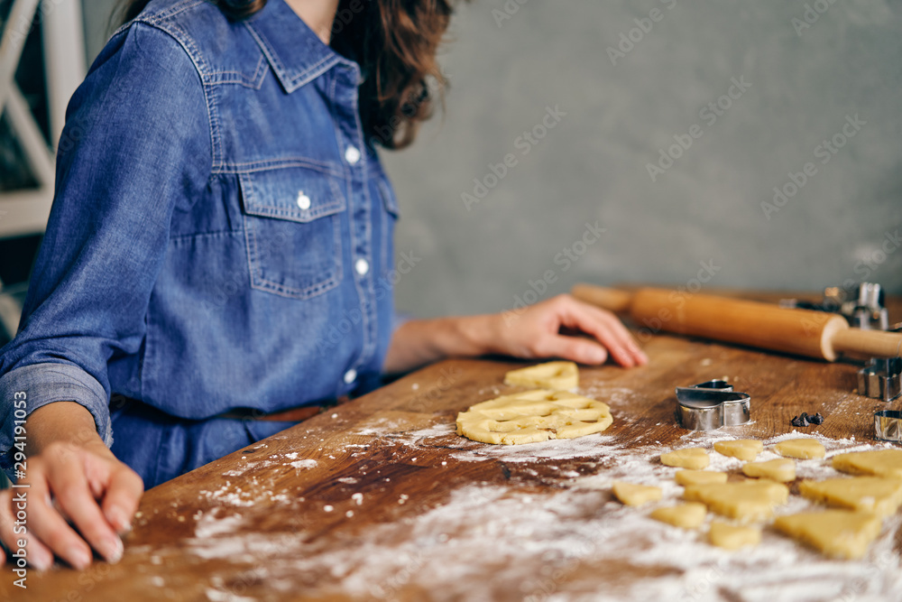 Young adult woman cooking holiday cookies in winter season at home