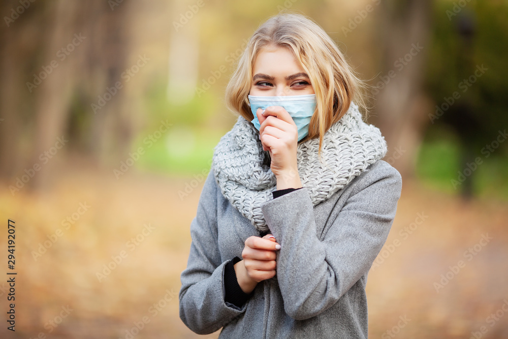 Cold and flu. Woman with a medical face mask at outdoor in autumn forest Cold and flu. Woman with a medical face mask at outdoor in autumn forest