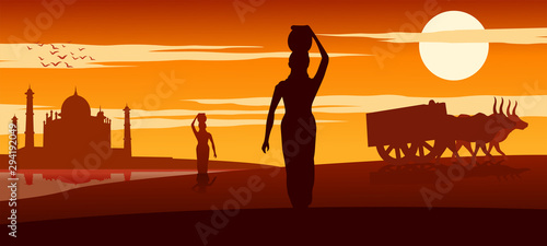 woman carry water for routine use from river near Taj mahal while cart move pass on sunset time