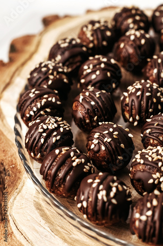 Round chocolates candy with sesame seeds. Dark background, luxury dessert, dark chocolate, handmade.