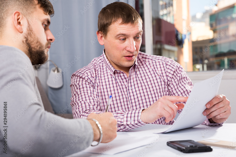 Obraz premium Focused man with partner reading papers at table