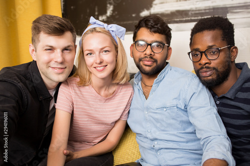 Cheerful multi-ethnic friends sitting on a sofa photo