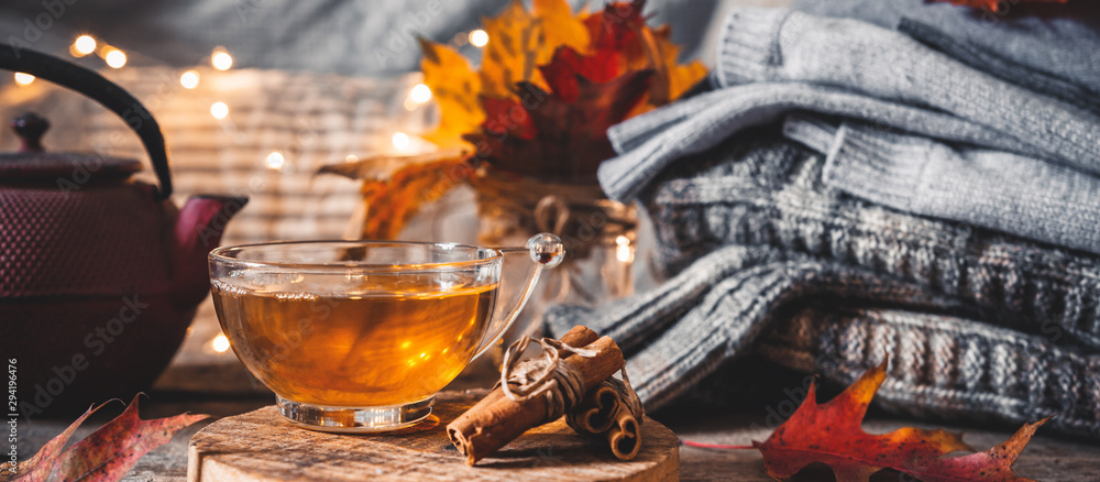 Cozy autumn or winter at home. A cup of tea, autumn casts a book a garland on a wooden table near a bed with warm plaids. Lifestyle autumn hygge lagom?concept of a holiday and autumn weekend.Banner Cozy autumn or winter at home. A cup of tea, autumn casts a book a garland on a wooden table near a bed with warm plaids. Lifestyle autumn hygge lagom?concept of a holiday and autumn weekend.Banner