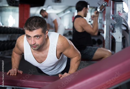 Man doing incline push-ups in gym