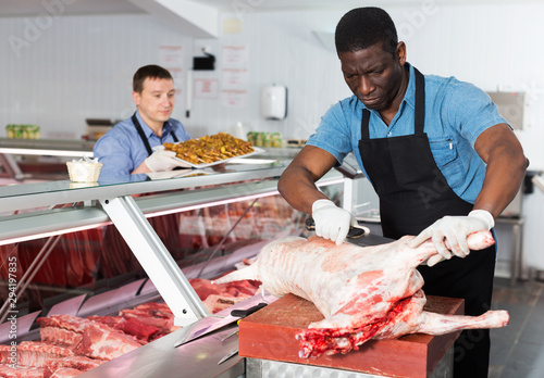 Foto African American male butcher processing carcase of lamb