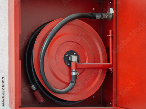 Wall mounted fire water hoses and fire fighting equipment on red cabinet