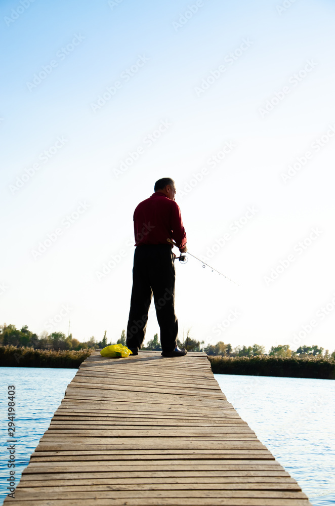 fisherman on a bridge near a blue lake
