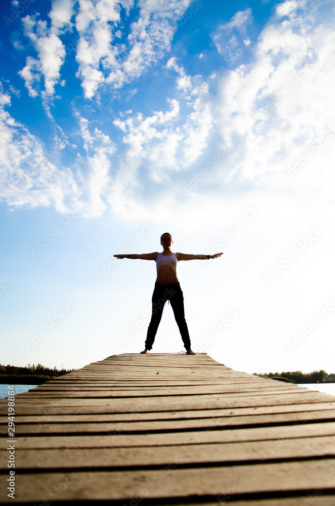 girl doing yoga and sports martial arts on a bridge on a lake girl doing yoga and sports martial arts on a bridge on a lake