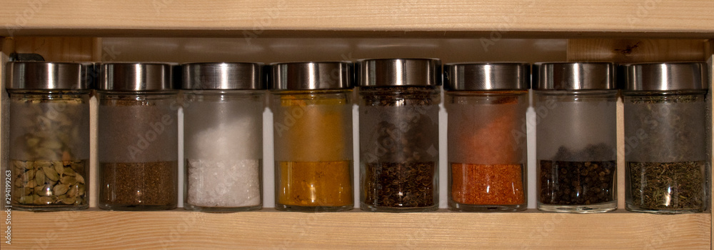 powder spices in glass bottle jar on a wooden shelf