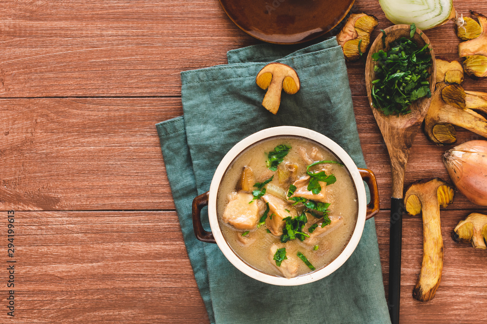 Forest mushroom soup with sour cream and parsley. Autumn food on wooden background. Forest mushroom soup with sour cream and parsley. Autumn food on wooden background.