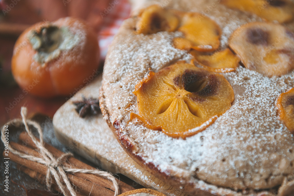 homemade cake with persimmon slices and powdered sugar and cinnamon closeup,