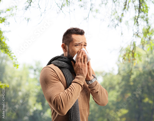 Young man blowing nose