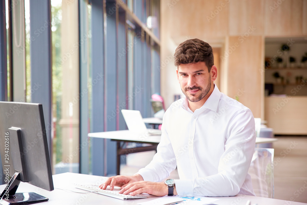 Professional businessman wearing shirt while working on computer in the office Professional businessman wearing shirt while working on computer in the office