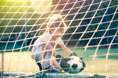 Disappointed football team goalkeeper following goals. Soccer Ball in the grid of gate  the team player pulls the scored the ball out of the goal on green field. Defeat Concept