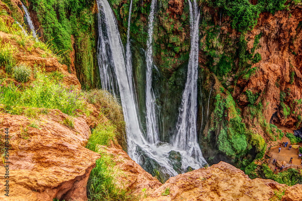 Landscape view of waterfall surrounded with green grass and orang colour terrain, Ouzoud Falls. Moyen Atlas village of Tanaghmeilt, Atlas mountains, Morocco.