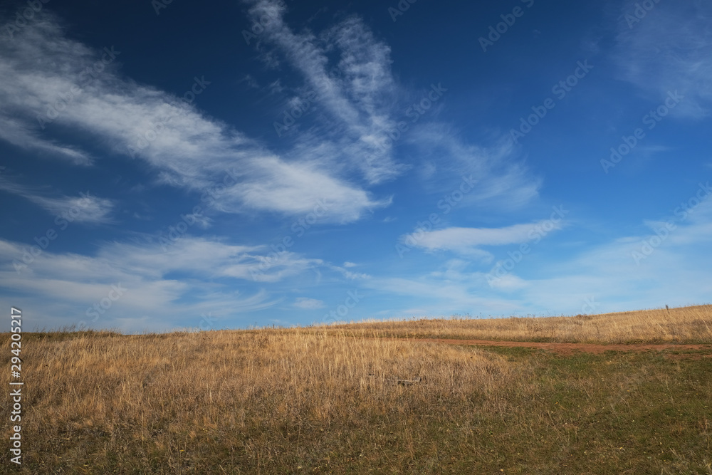 autumn steppe and blue sky with cloudy clouds