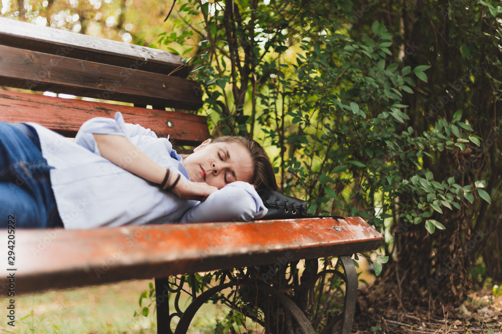 Fototapeta premium Woman sleeping on a bench outdoors