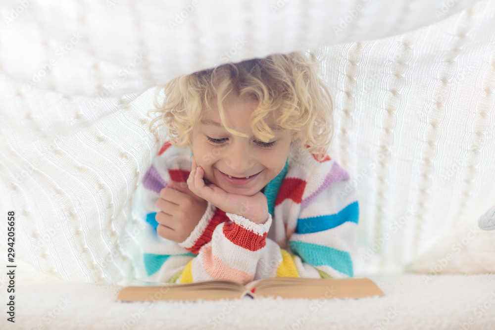 Fototapeta premium Child reading book in bed. Kids read books.
