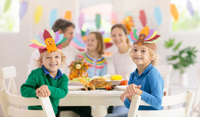 Family with kids at Thanksgiving dinner. Turkey.